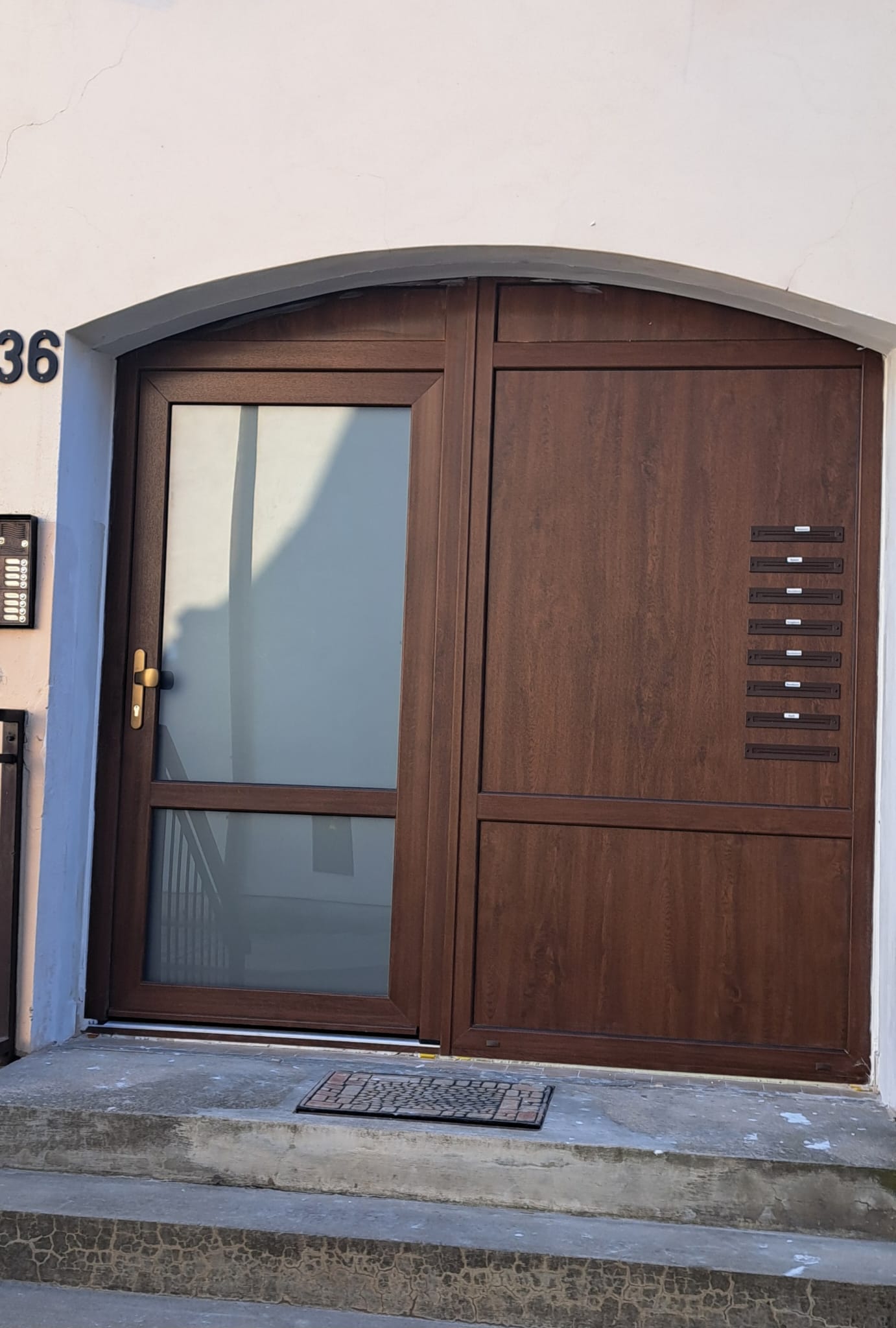 Hnědé vchodové dveře s obloukovým záklenkem ve starší fasádě