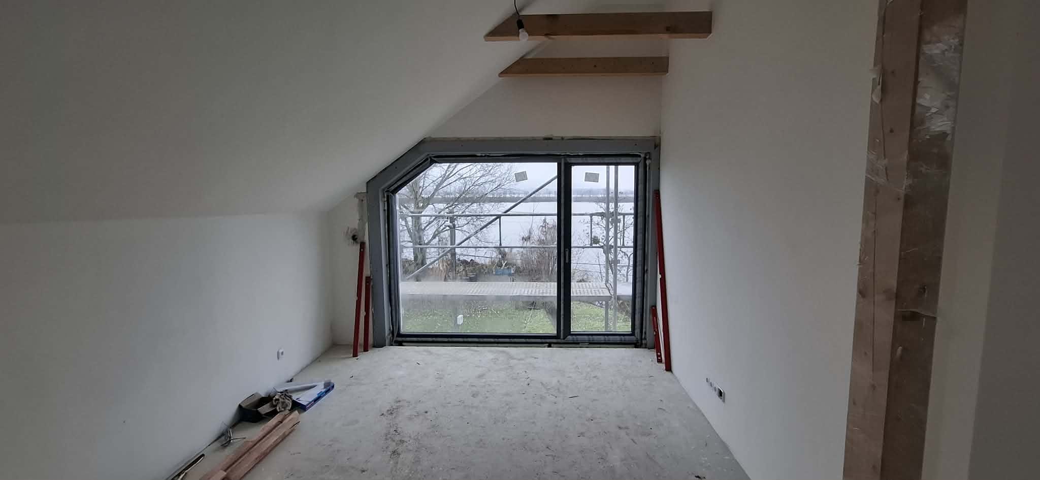 Velké šikmé podkrovní okno v dokončovaném pokoji
